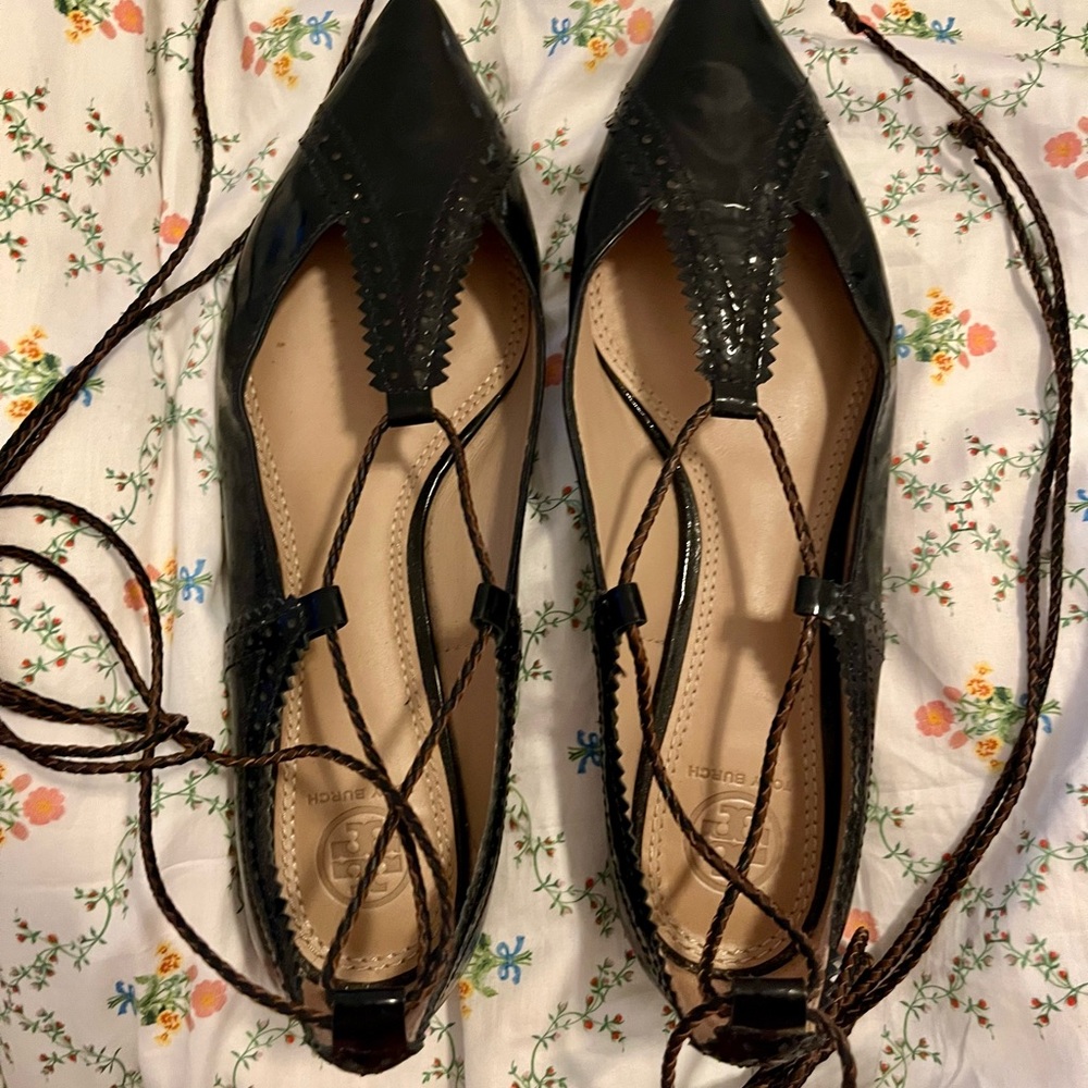 Black lace up Tory Burch flats with brown detailing.